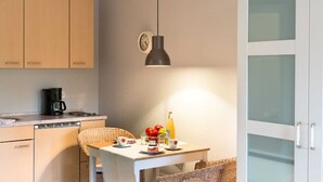 Una cocina compacta con comedor, un reloj y una botella de jugo sobre la mesa.