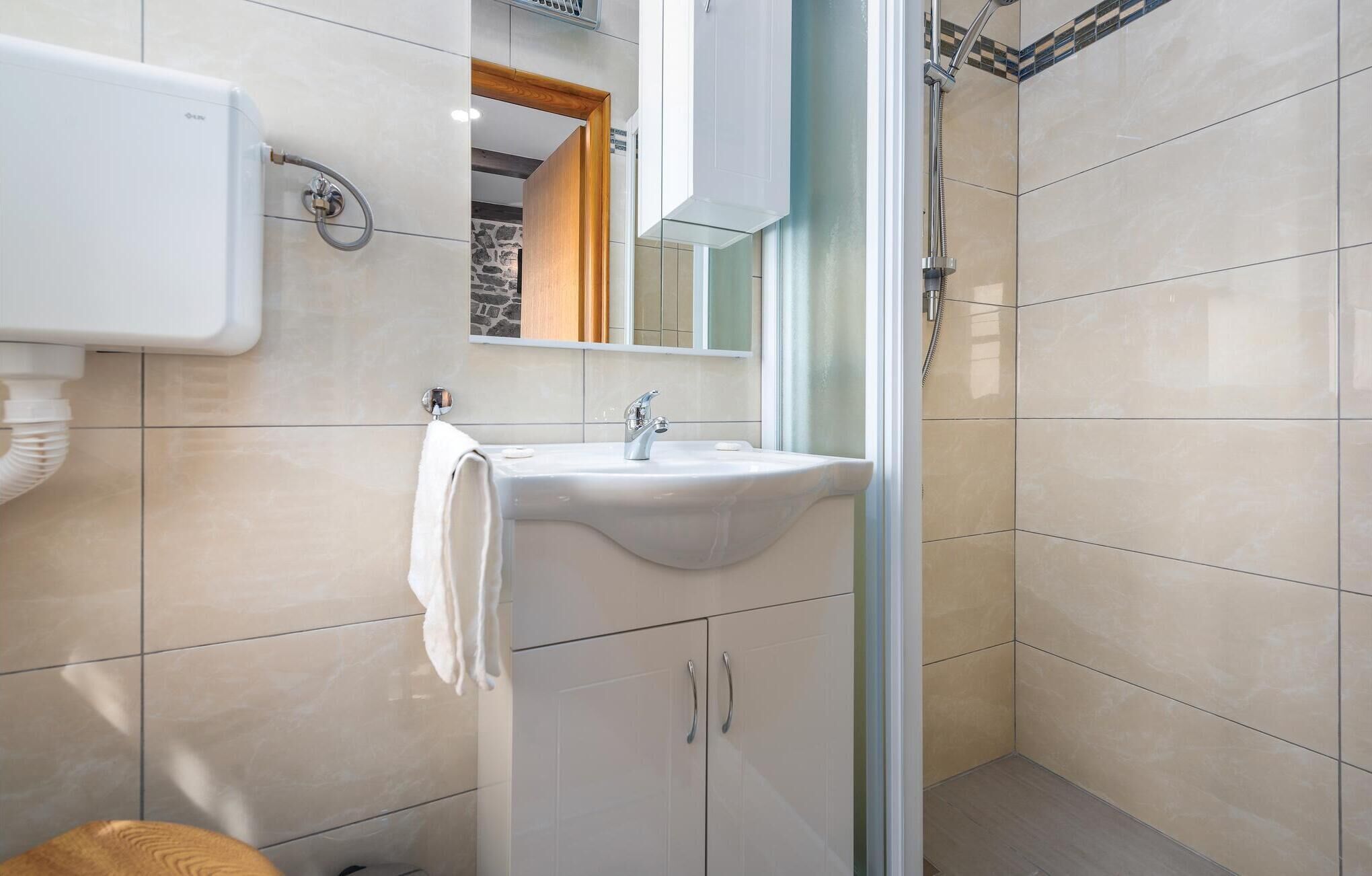 A modern bathroom with a white sink, a mirror, and a shower.
