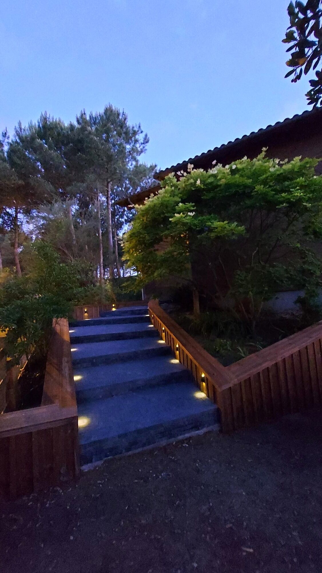 A staircase leading up to a building with a wooden railing and a stone wall.
