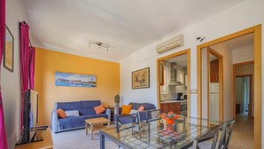Una sala de estar moderna con una mesa de comedor de vidrio, dos sofás y una cocina al fondo.