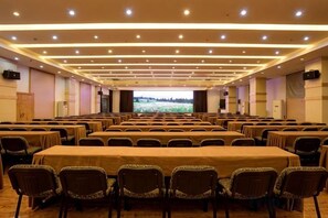 A conference room with rows of tables and chairs, a large screen at the front, and a projector. - Qingcheng Country Villa (Dujiangyan)