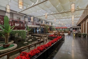 A spacious indoor area with a water feature, wooden walkways, and hanging light fixtures.