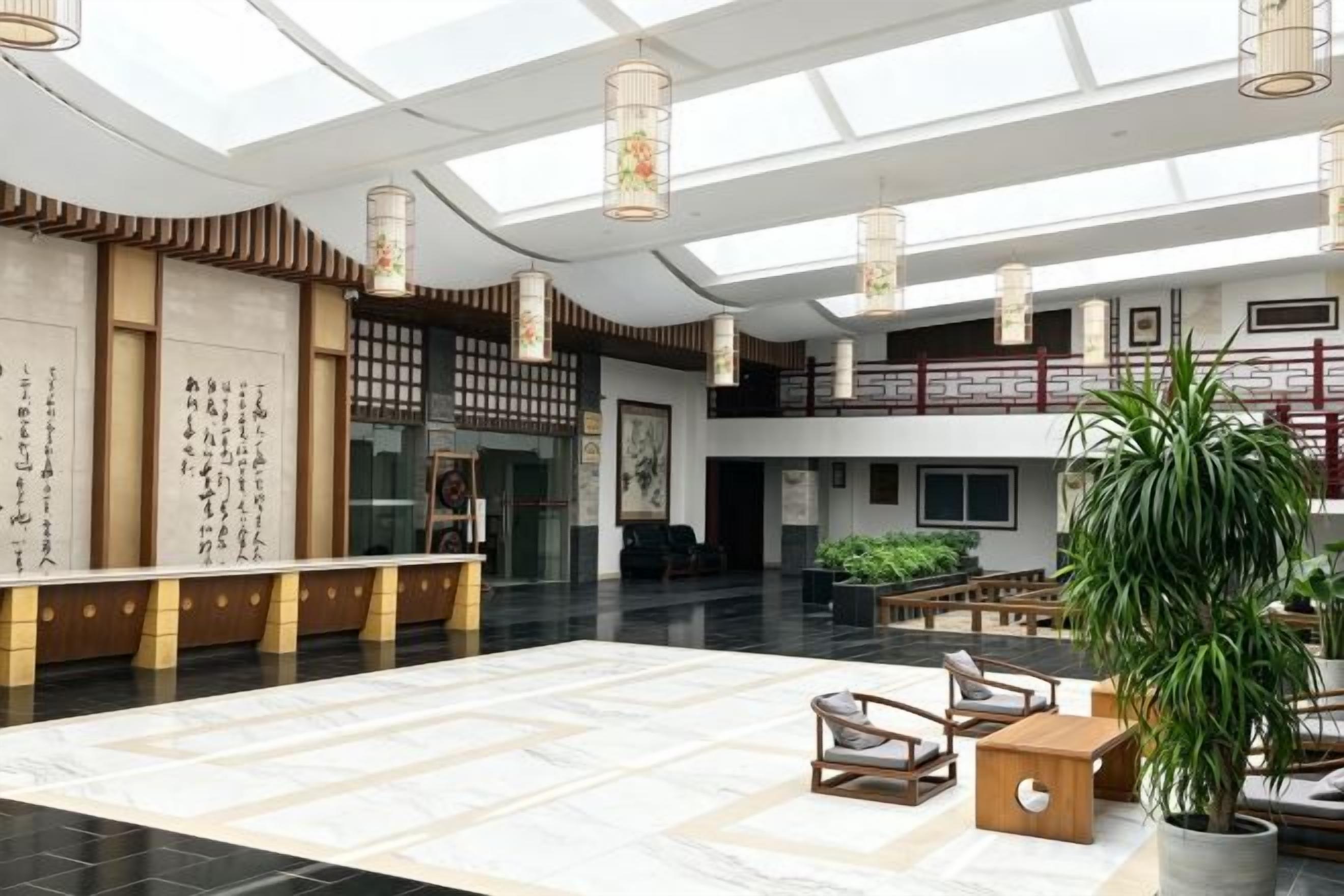 Un hall amplio con techo alto, una recepción, una zona de estar y una escalera.