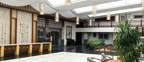 Un hall amplio con techo alto, una recepción, una zona de estar y una escalera.