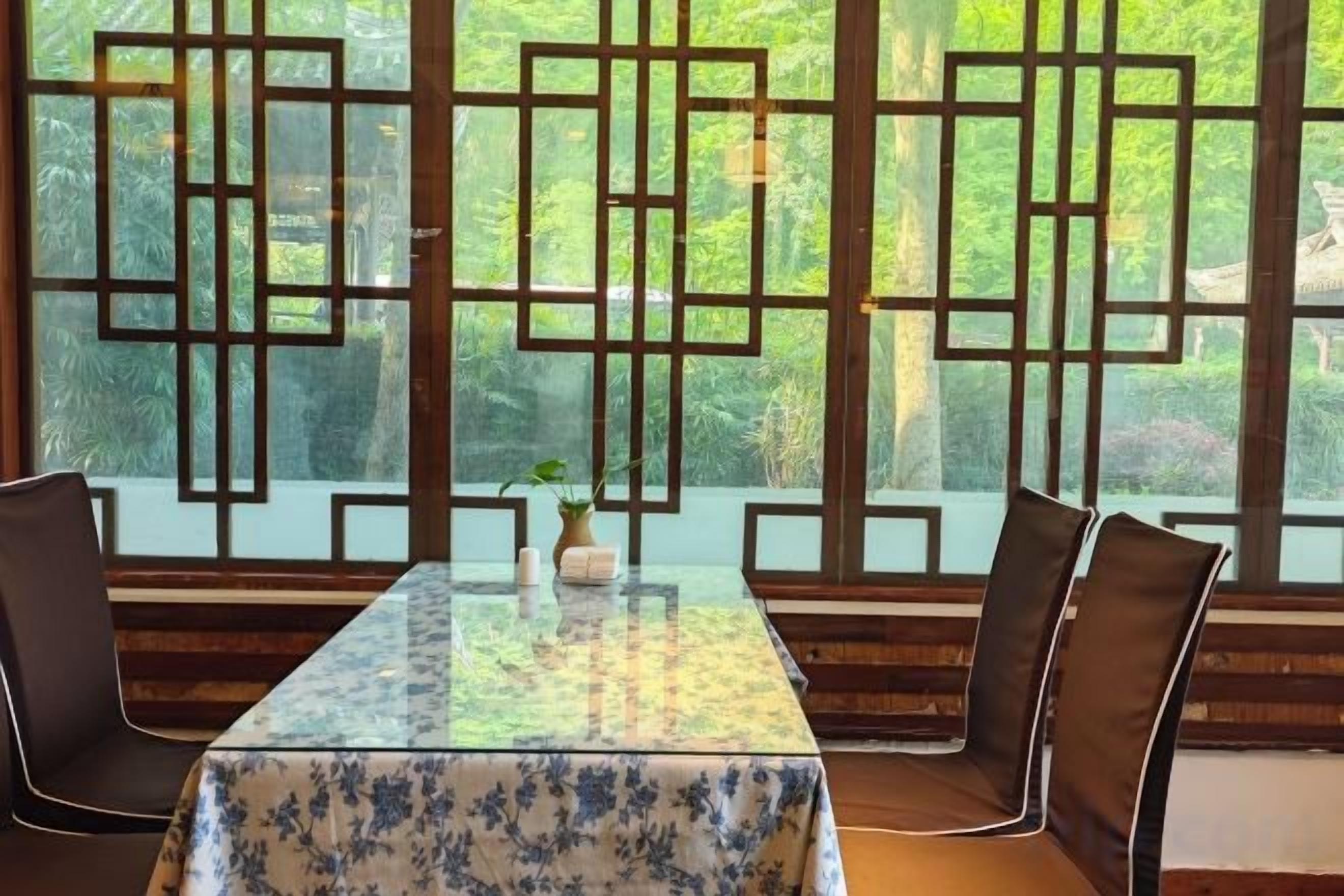A dining area with a table and chairs, a decorative screen, and a view of greenery.