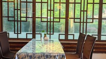 A dining area with a table and chairs, a decorative screen, and a view of greenery.