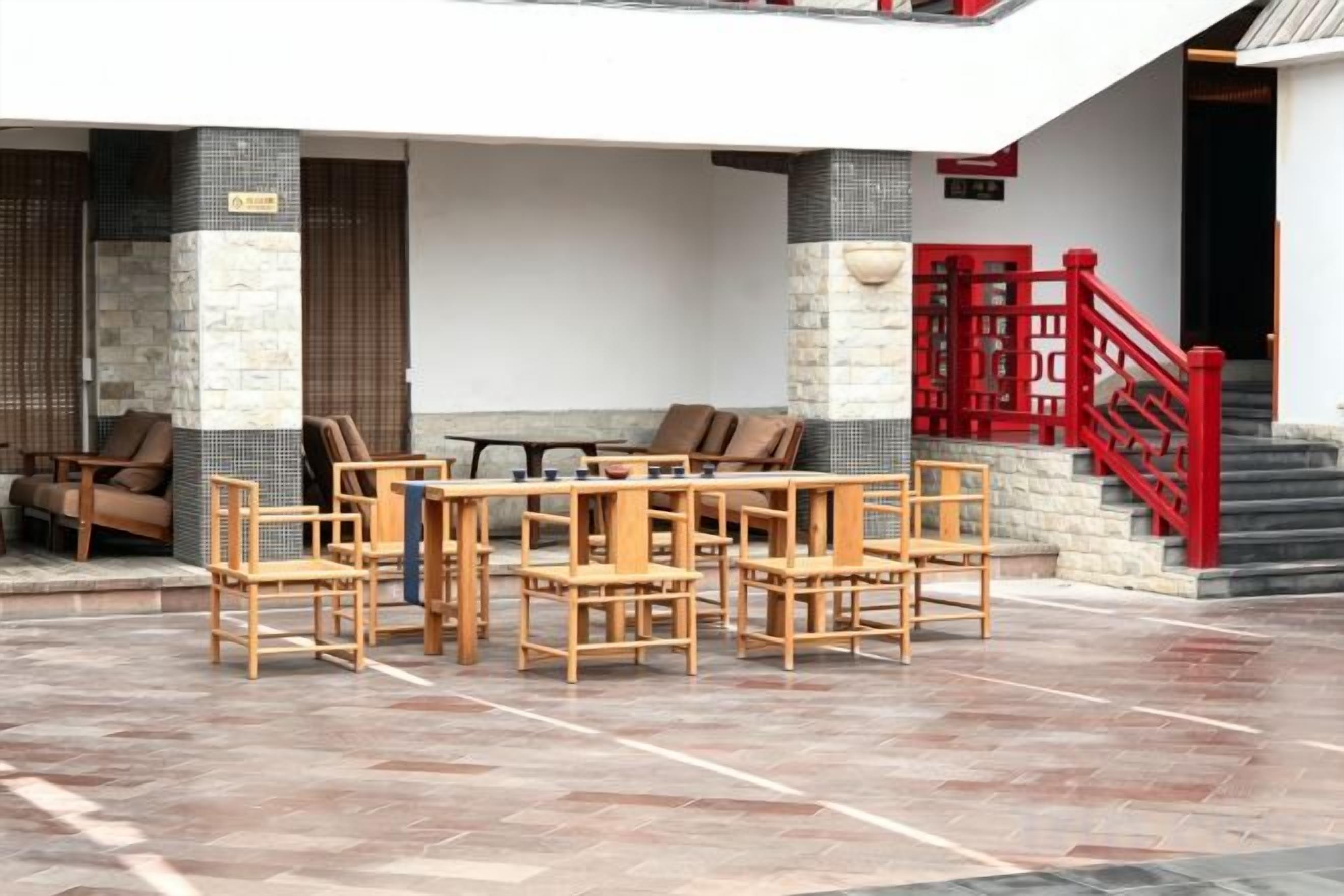 Un'area salotto esterna con mobili in legno e una scala rossa.