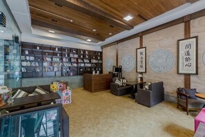 Zona de recepción con techo de madera, vitrina de cristal y pared decorada con obras enmarcadas.