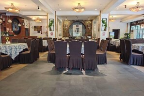 A restaurant with multiple tables and chairs, a central decorative wall, and overhead lighting. - Qingcheng Country Villa (Dujiangyan)