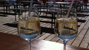 Two glasses of wine on a wooden table with a mountain view in the background. - New, stylish top floor apartement, free Wifi, bus stop directly at the house (Ramsau im Zillertal)