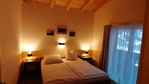 A small, cozy bedroom with a single bed, two bedside lamps, and a window with curtains. - New, stylish top floor apartement, free Wifi, bus stop directly at the house (Ramsau im Zillertal)