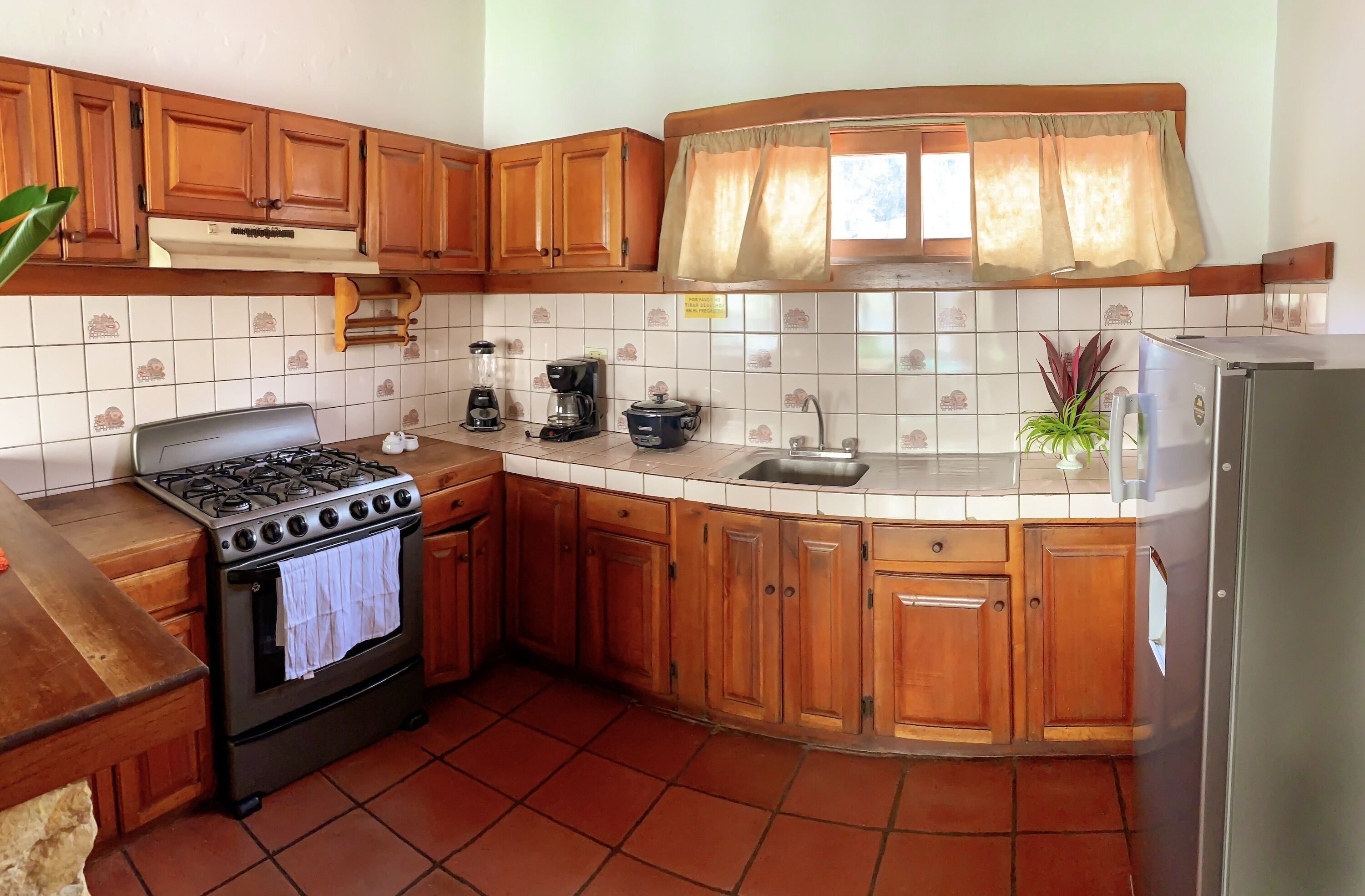 A kitchen with wooden cabinets, a stove, a sink, and a refrigerator.