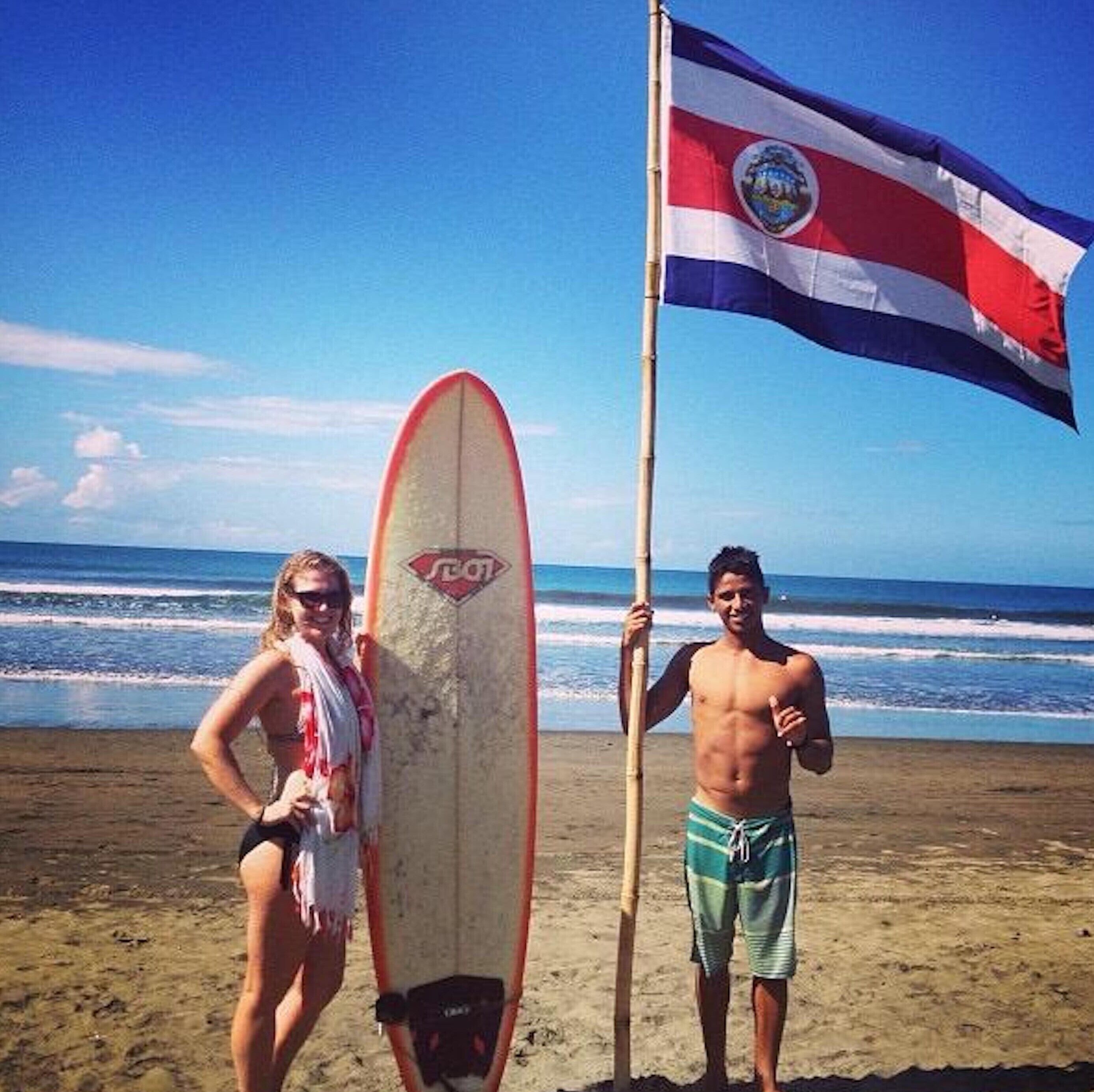 A beach scene with a surfboard and a flag.
