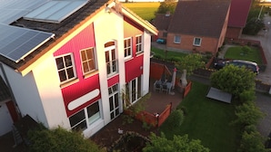 Uma casa de dois andares com fachada vermelha e um painel solar no telhado.