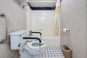Bathroom features a white toilet with safety rail and a bathtub with shower curtain.
