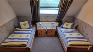 A small, cozy room with two single beds, a nightstand with a lamp, and a window with curtains. - Enjoy the tranquility of this landscape that has something to offer for everyone. Dollard (Bunde-Dollart)