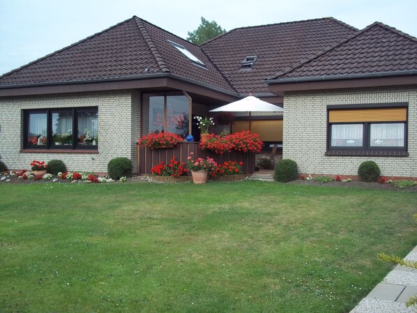 A two-story house with a brick facade, large windows, and a well-maintained lawn.