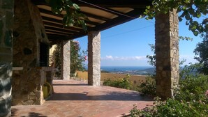 A stone building with a tiled patio and a view of the sea.