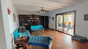 A living room with a sofa, a coffee table, a bookshelf, and a sliding glass door leading to an outdoor patio.