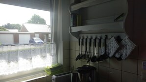 A kitchen with a window, a stove, and hanging kitchen utensils. - Good Morning! Welcome to East Frisia! (Berumbur)