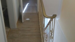 A staircase with a wooden handrail and a door leading to another room. - Good Morning! Welcome to East Frisia! (Berumbur)