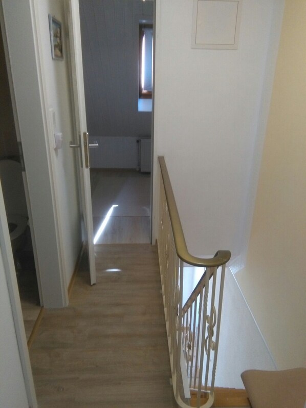 Una escalera con barandal de madera y una puerta que da a otra habitación.