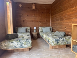 Una cabaña de madera con dos literas, un taburete tejido y una lámpara colgante.