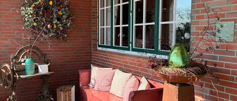 A brick-walled room with a red sofa, a green window, and a decorative wreath.