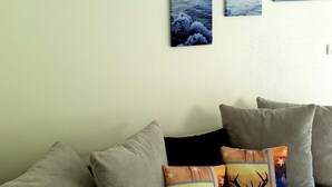 A living room with a grey sofa, three framed landscape paintings, and decorative pillows. - Apartment in a quiet location (Fügenberg)