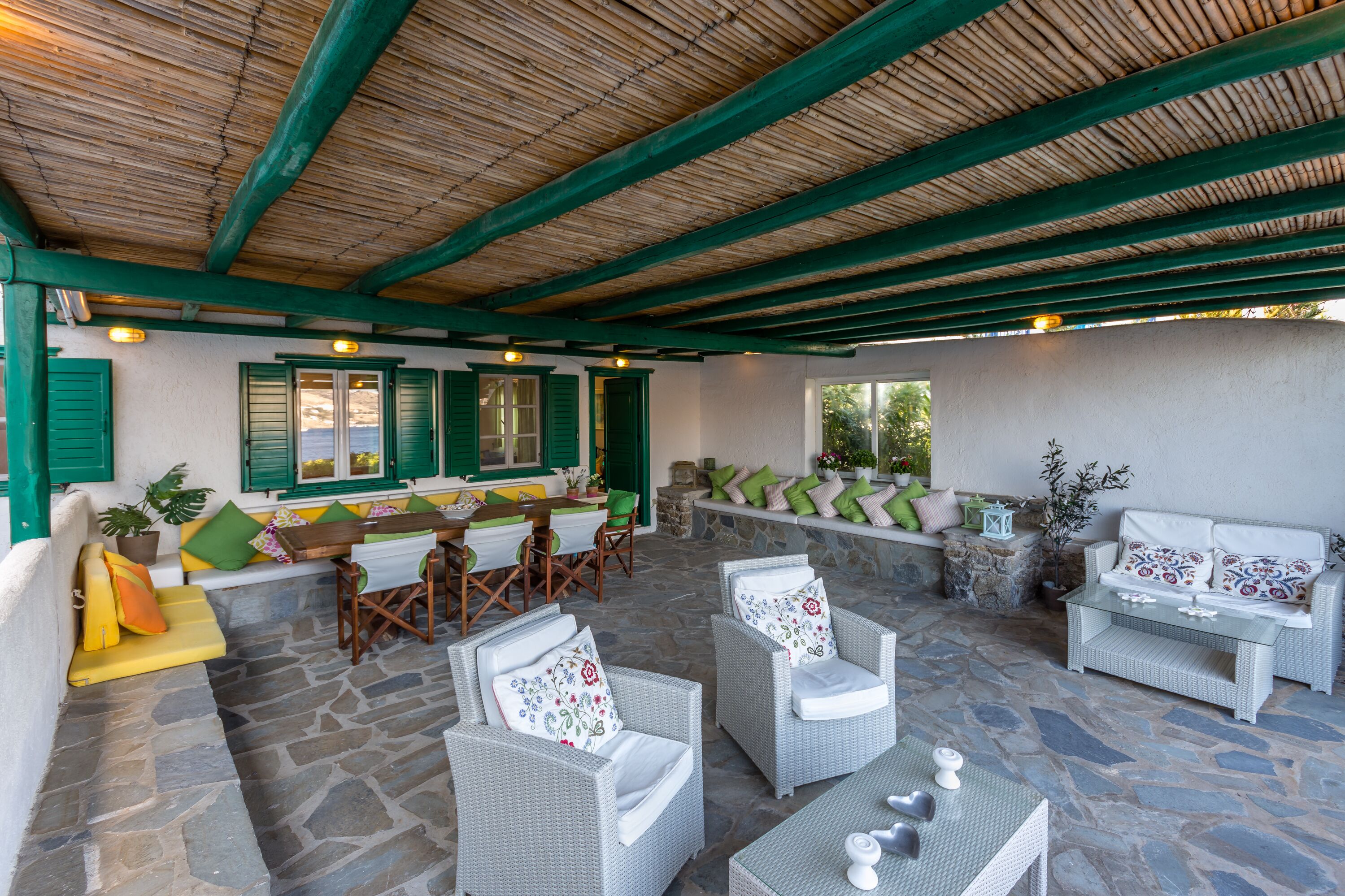 An outdoor patio with stone flooring, wicker furniture, and a wooden ceiling.