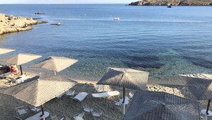 Una playa con agua cristalina, sillas de descanso y sombrillas.