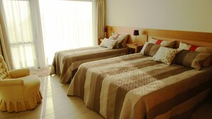 Una habitación de hotel con dos camas, una silla y una mesita de noche con lámpara.