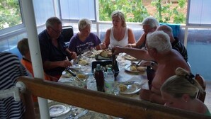 Un grupo de personas cenando en una mesa con vistas a la vegetación.