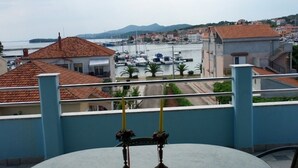 Un balcón con una mesa y dos velas, con vistas a un puerto deportivo con barcos y edificios.