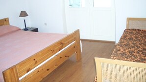 Un dormitorio con dos camas, una mesita de noche, una lámpara y una ventana.