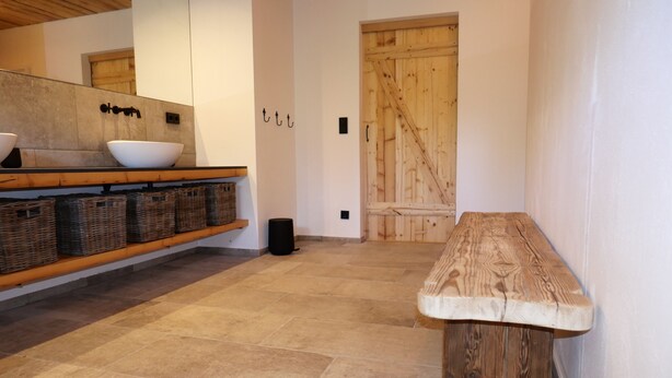 A modern kitchen with a wooden bench, stone tiles, and wicker baskets. - Historic Burggen vicarage with large garden, near Neuschwanstein Castle (Burggen)