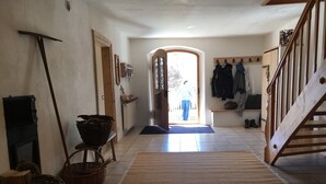 A hallway with a wooden staircase, a radiator, a door leading outside, and a bench with baskets. - Historic Burggen vicarage with large garden, near Neuschwanstein Castle (Burggen)