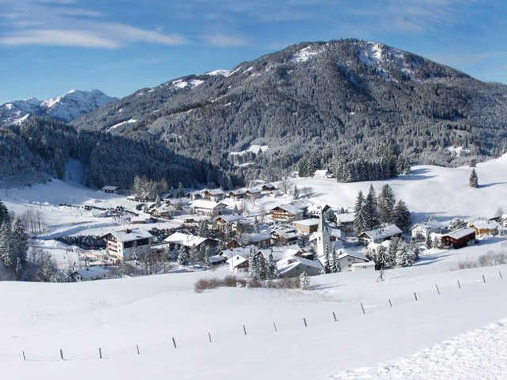 A snow-covered mountain town with buildings and a ski slope.