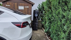 Een witte auto geparkeerd voor een gebouw met een houten deur en een bord.