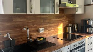 Een moderne keuken met houten kastjes, een roestvrijstalen spoelbak, een inbouwoven en een magnetron.