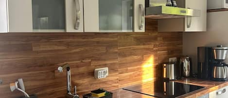 A modern kitchen with wooden cabinetry, a stainless steel sink, a built-in oven, and a microwave.