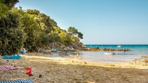 A beach with clear skies, a rocky shoreline, and people enjoying the water. - Beach Villa: private bathing area, sandy beach, WiFi, ideal for families (Novalja)