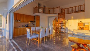 A spacious living area with a dining table, chairs, a sofa, and a wooden staircase connecting two floors. - Beach Villa: private bathing area, sandy beach, WiFi, ideal for families (Novalja)