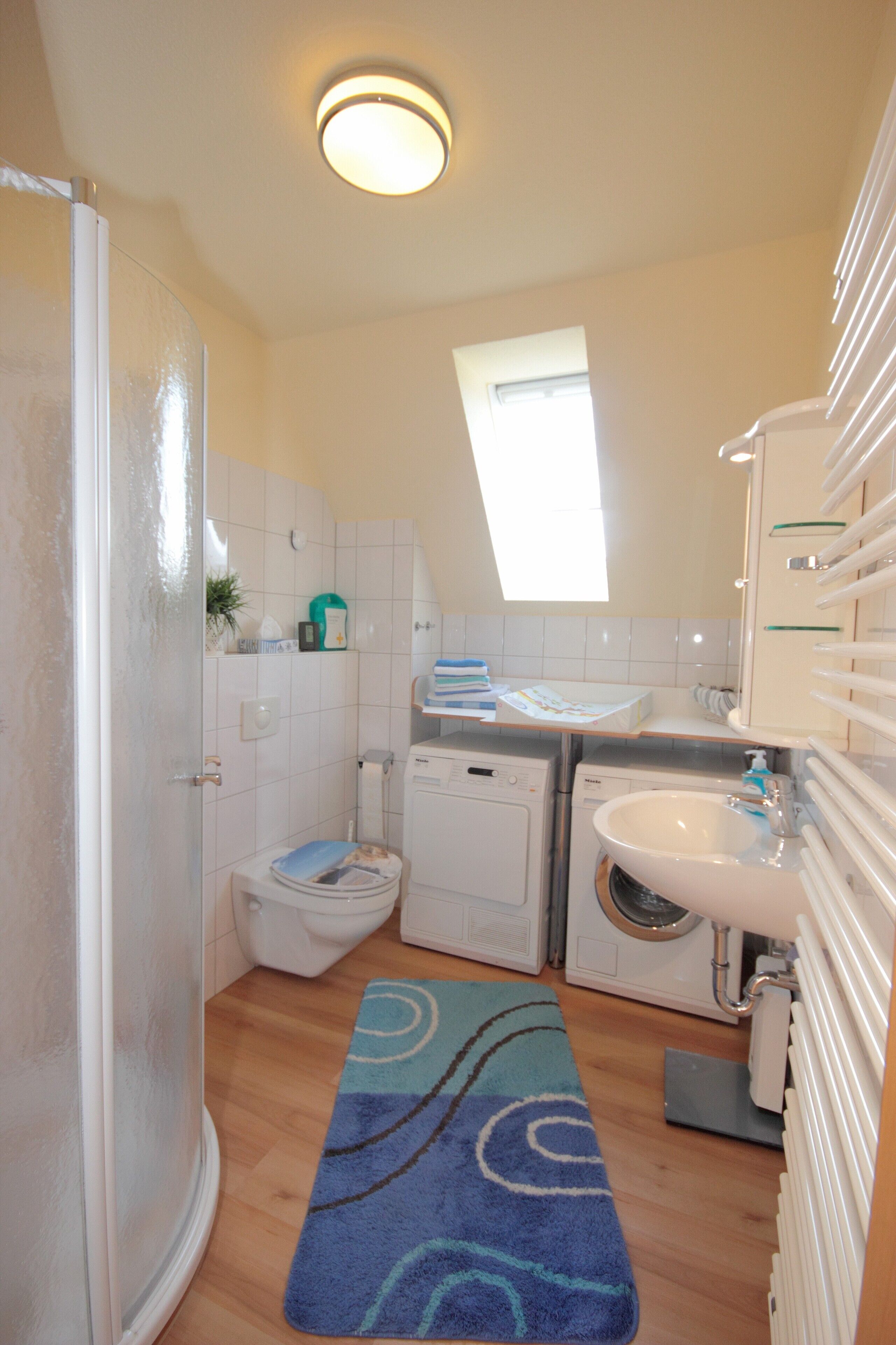 A compact bathroom with a toilet, washing machine, and sink.