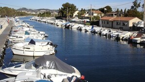 A marina with numerous boats docked along a narrow waterway, surrounded by buildings and trees.