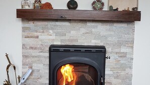 A fireplace with a stone facade, a mantel with decorative items, and a painting above it. - Cottage on Lough Ree / River Shannon in the heart of Ireland (Newtowncashel)