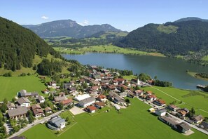 Zona residencial con casas y un lago, rodeada de montañas.