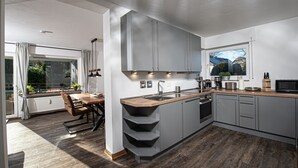 Uma cozinha moderna com armários cinzentos, bancada de madeira e forno embutido.