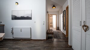 Um corredor com um radiador, um banco, um quadro pendurado na parede e uma porta com puxador em formato de coração.