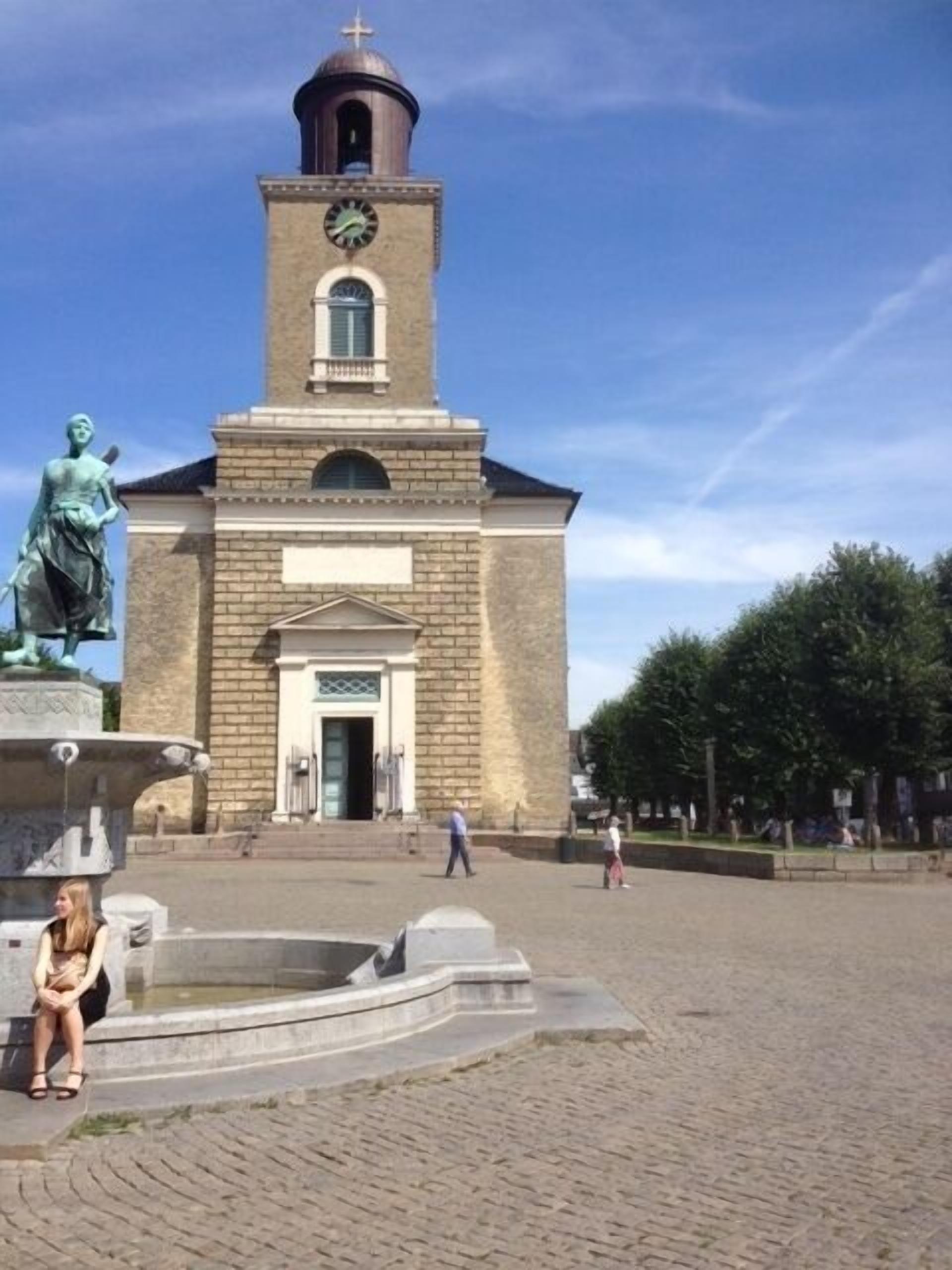 Une église dotée d’un clocher, d’une statue et d’une fontaine à l’avant.